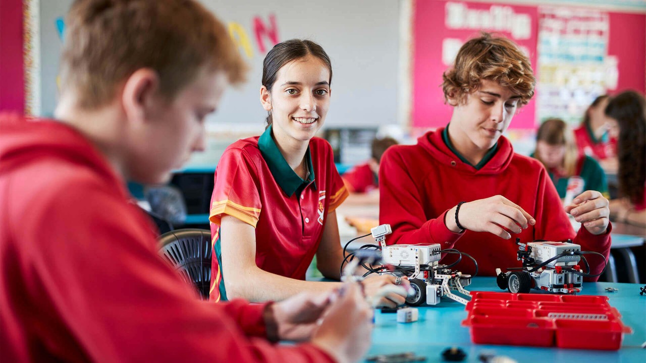 High school students working with robotics at a classroom table.